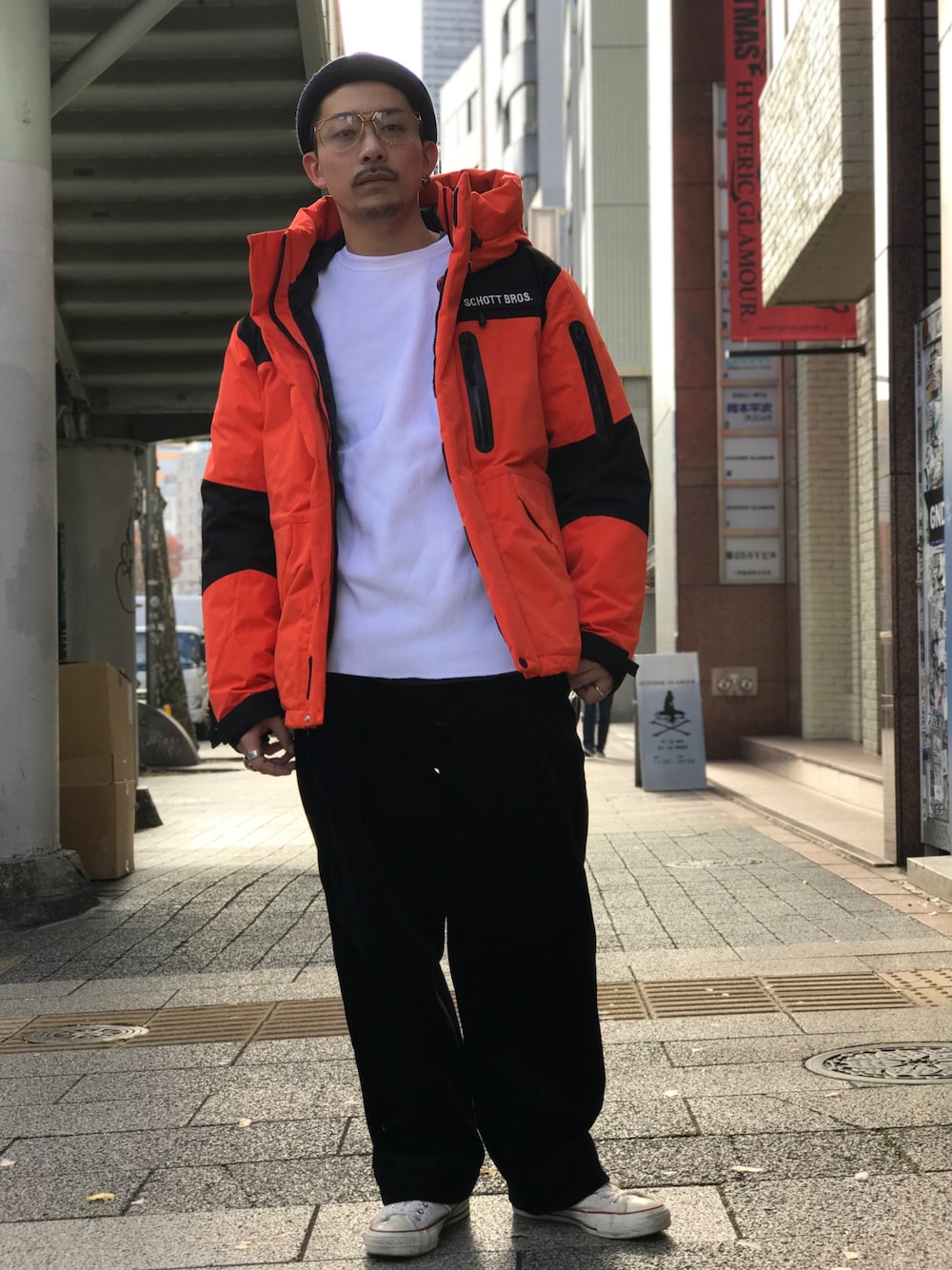 ホワイト系のTシャツ/カットソー、オレンジ系のダウンジャケット/コート、ホワイト系のシューズを着用したメンズの秋コーディネートの1枚目の写真