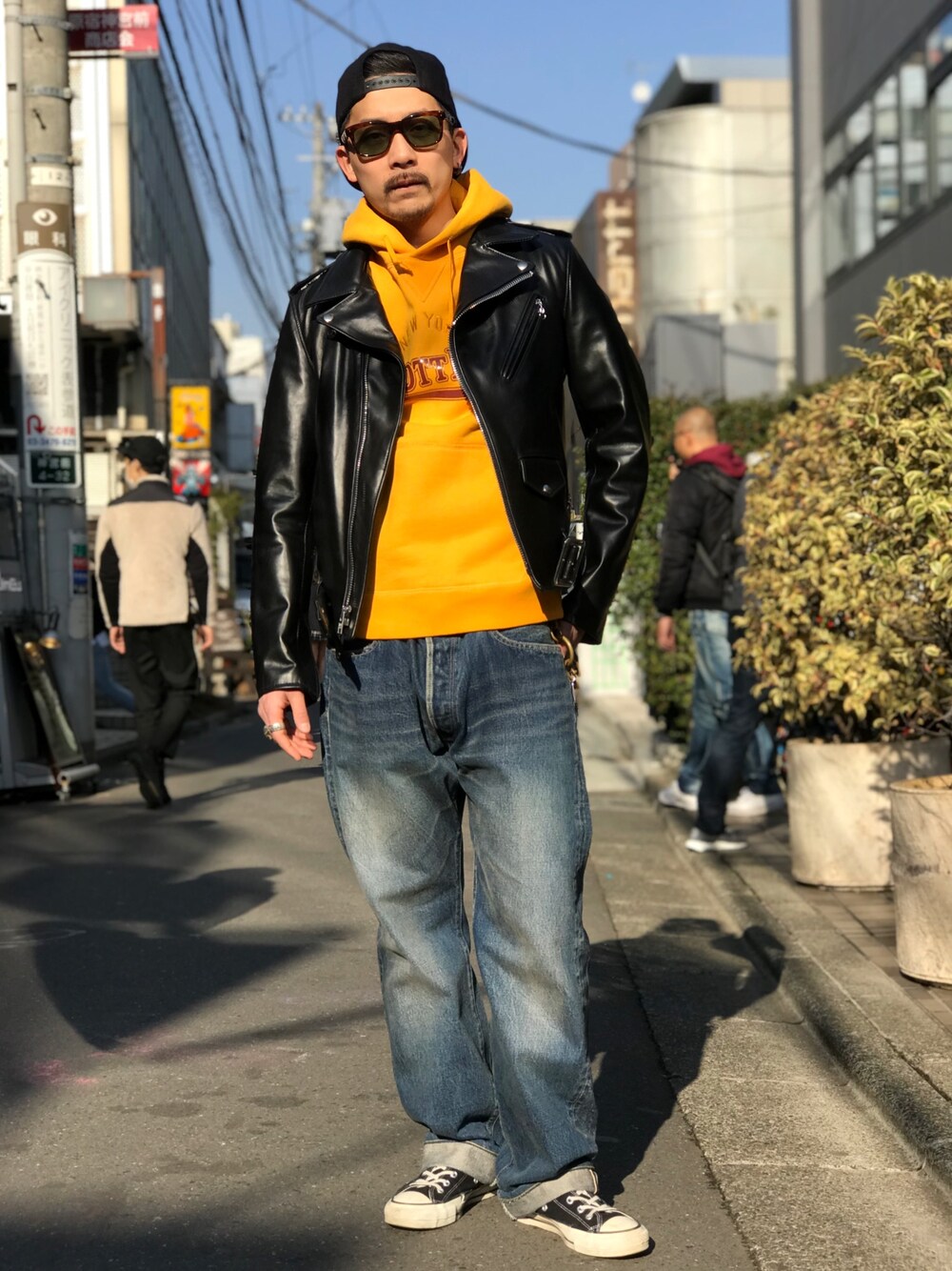 イエロー系のパーカー、ブラック系のスニーカー、ブルー系のデニムパンツを着用したメンズの冬コーディネートの1枚目の写真