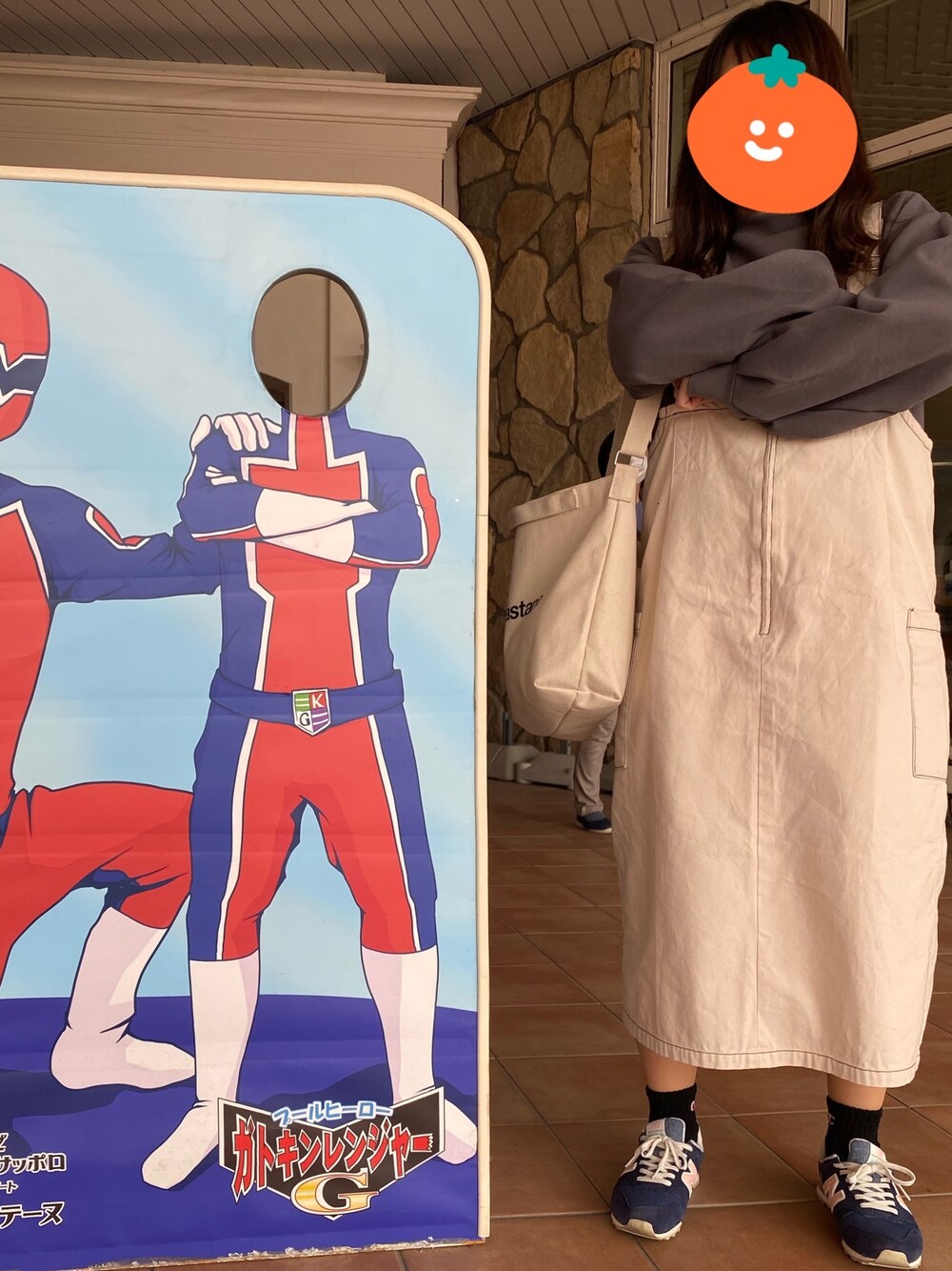 グレー系のトップス、ホワイト系のジャンパースカート、ブルー系のスニーカーを着用したレディースの春コーディネートの1枚目の写真