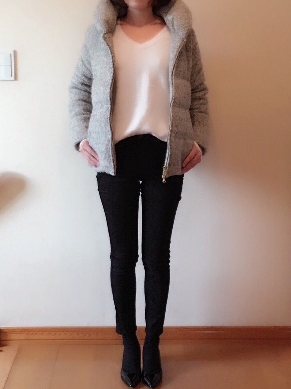 ブラック系のデニムパンツ、グレー系のダウンジャケット/コート、ブラック系のパンプスを着用したレディースの冬コーディネートの1枚目の写真