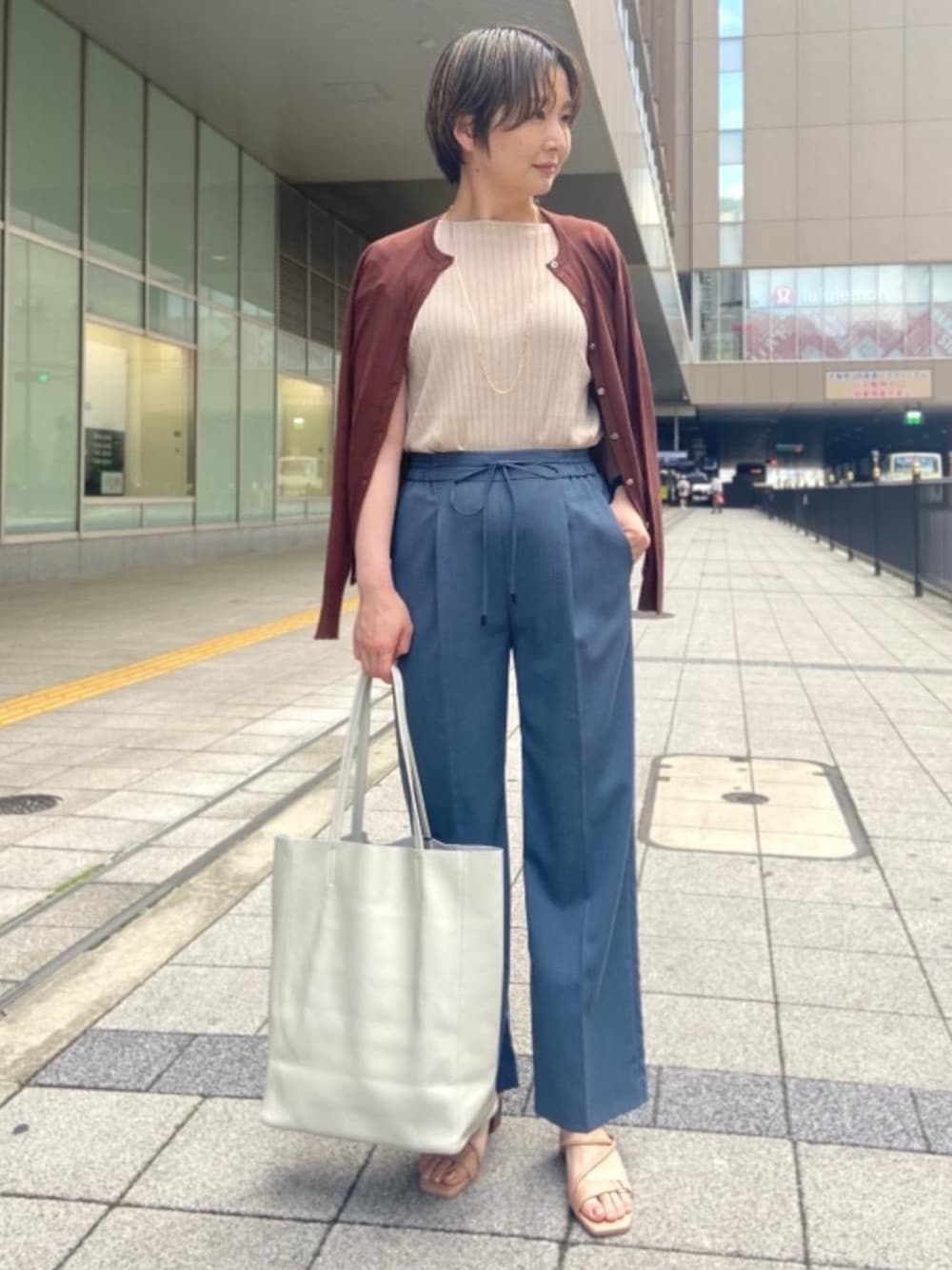 ブラウン系のカーディガン/ボレロ、ベージュ系のサンダル、ブルー系のその他パンツを着用したレディースの春コーディネートの1枚目の写真