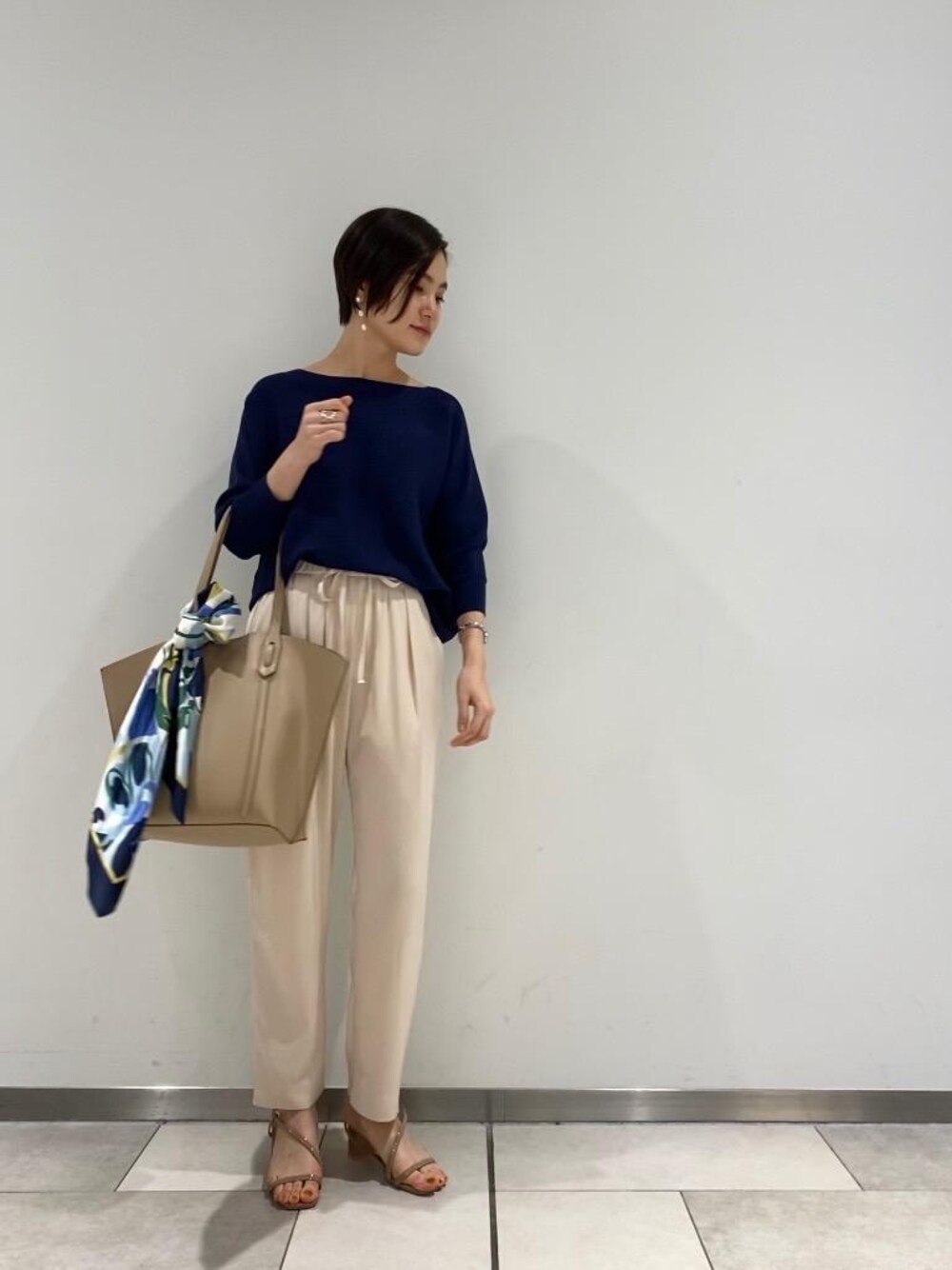 ベージュ系のその他パンツ、ブルー系のニット/セーター、ベージュ系のショルダーバッグを着用したレディースの春コーディネートの1枚目の写真