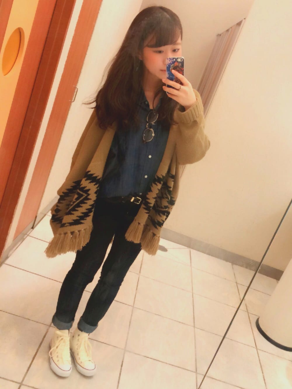 ブラウン系のポンチョ、ホワイト系のスニーカー、ブルー系のパンツを着用したレディースの春コーディネートの1枚目の写真