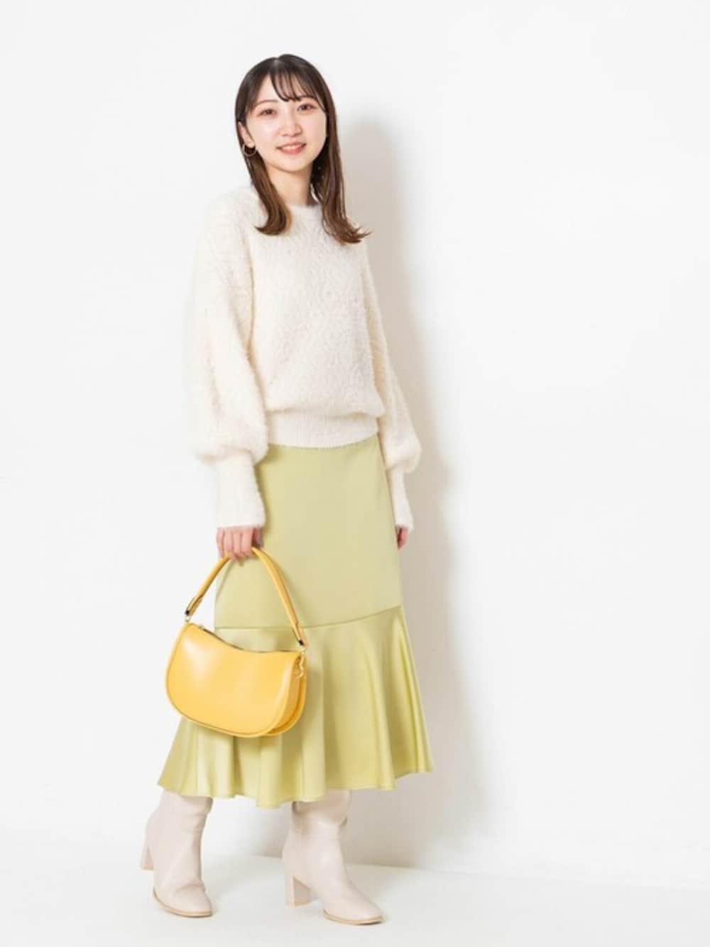 ベージュ系のニット/セーター、イエロー系のスカート、イエロー系のショルダーバッグを着用したレディースの冬コーディネートの1枚目の写真