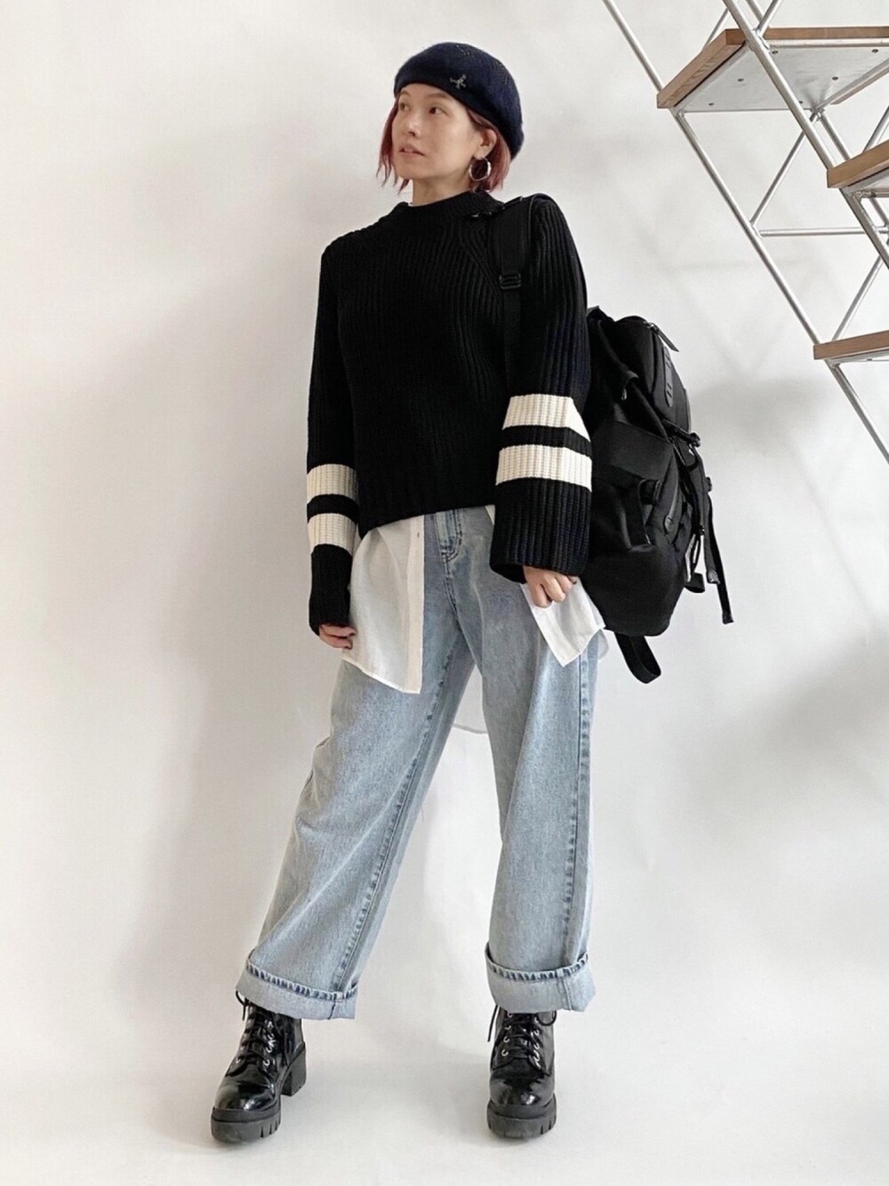 ブラック系のニット/セーター、ブルー系のデニムパンツ、ブラック系のブーツを着用したレディースの秋コーディネートの1枚目の写真