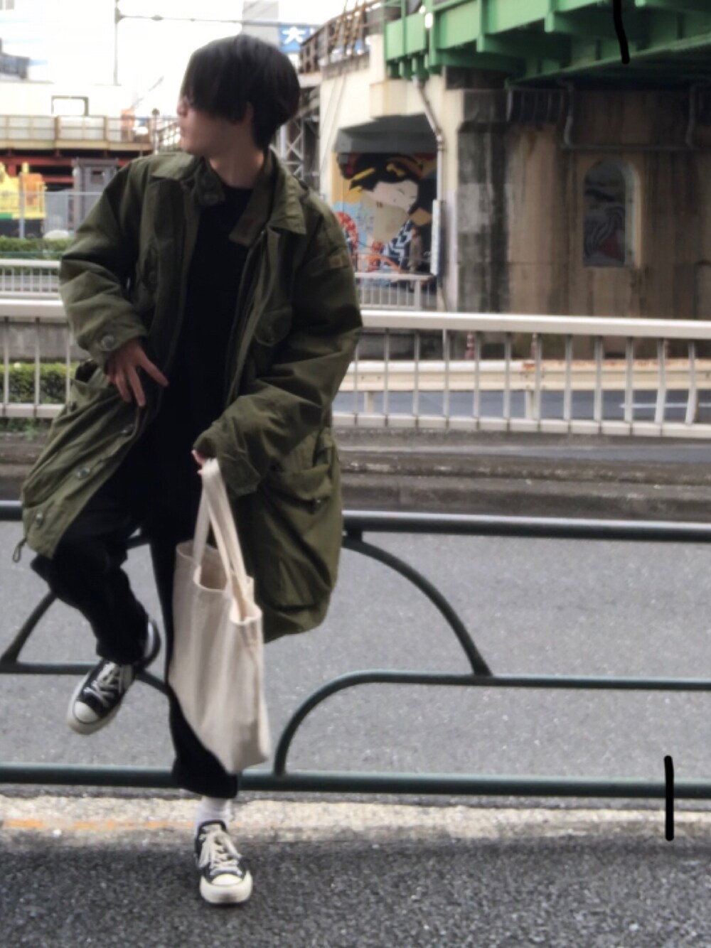 グリーン系のモッズコート、ベージュ系のトートバッグ、ブラック系のスニーカーを着用したメンズの春コーディネートの1枚目の写真