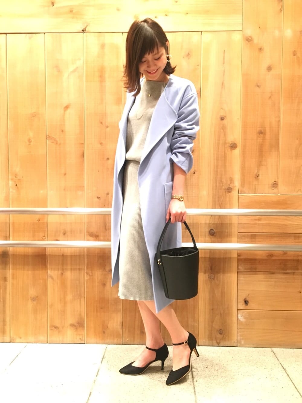 グレー系のワンピース、ブラック系のパンプス、ブラック系のショルダーバッグを着用したレディースの冬コーディネートの1枚目の写真