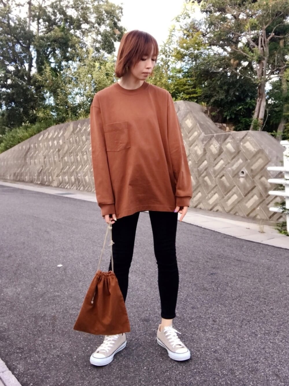 ブラウン系のTシャツ/カットソー、ブラック系のデニムパンツ、ブラウン系のハンドバッグを着用したレディースの秋コーディネートの1枚目の写真