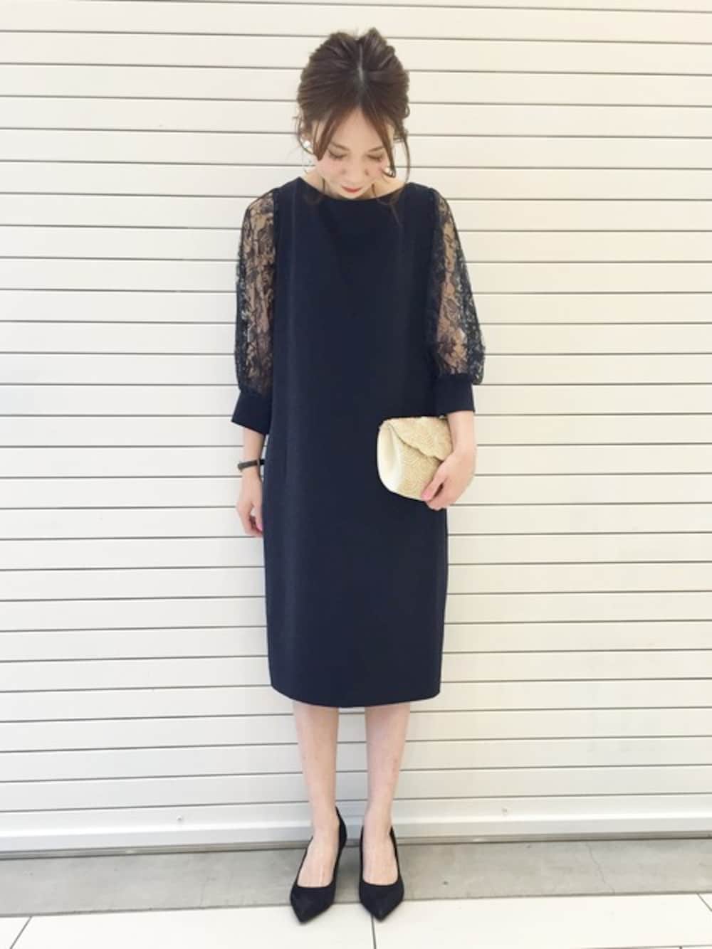 ブルー系のドレス、ブラック系のパンプス、ゴールド系のクラッチバッグを着用したレディースの春コーディネートの1枚目の写真