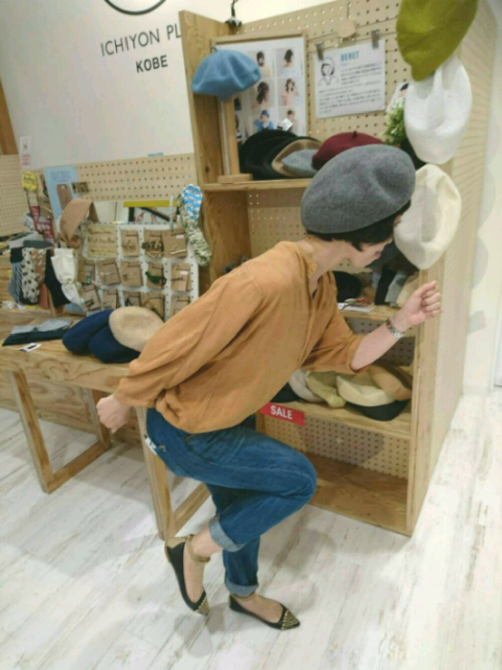 オレンジ系のトップス、ブルー系のデニムパンツ、グレー系のハンチング/ベレー帽を着用したレディースの秋コーディネートの1枚目の写真