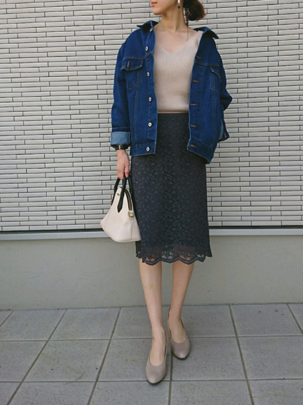 ベージュ系のニット/セーター、ホワイト系のハンドバッグ、グレー系のスカートを着用したレディースの春コーディネートの1枚目の写真