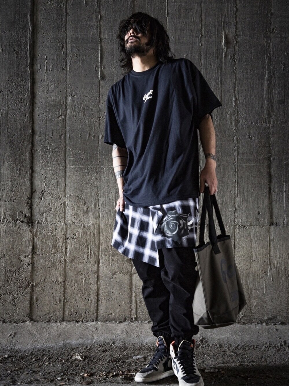 ブラック系のTシャツ/カットソー、ブラック系のスカート、ブラウン系のトートバッグを着用したメンズの春コーディネートの1枚目の写真