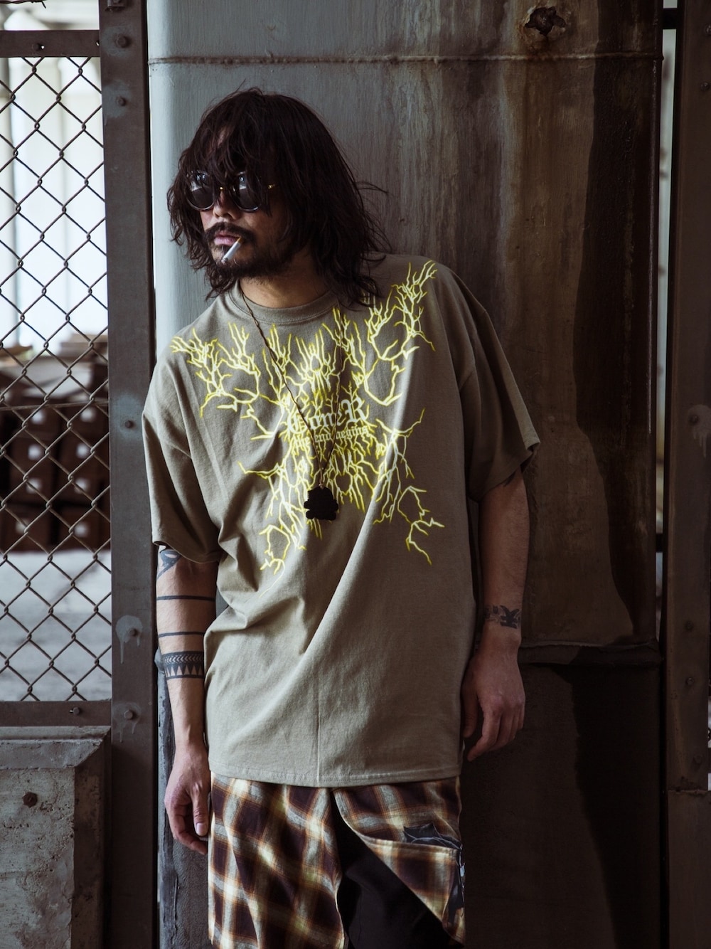 ブラウン系のTシャツ/カットソー、ブラウン系のスカート、ブラック系のネックレスを着用したメンズの夏コーディネートの1枚目の写真