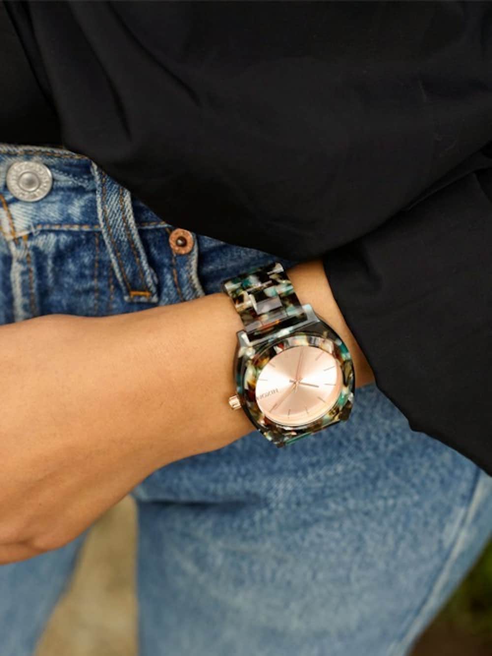 グリーン系のアナログ腕時計を着用したレディースの秋コーディネートの1枚目の写真