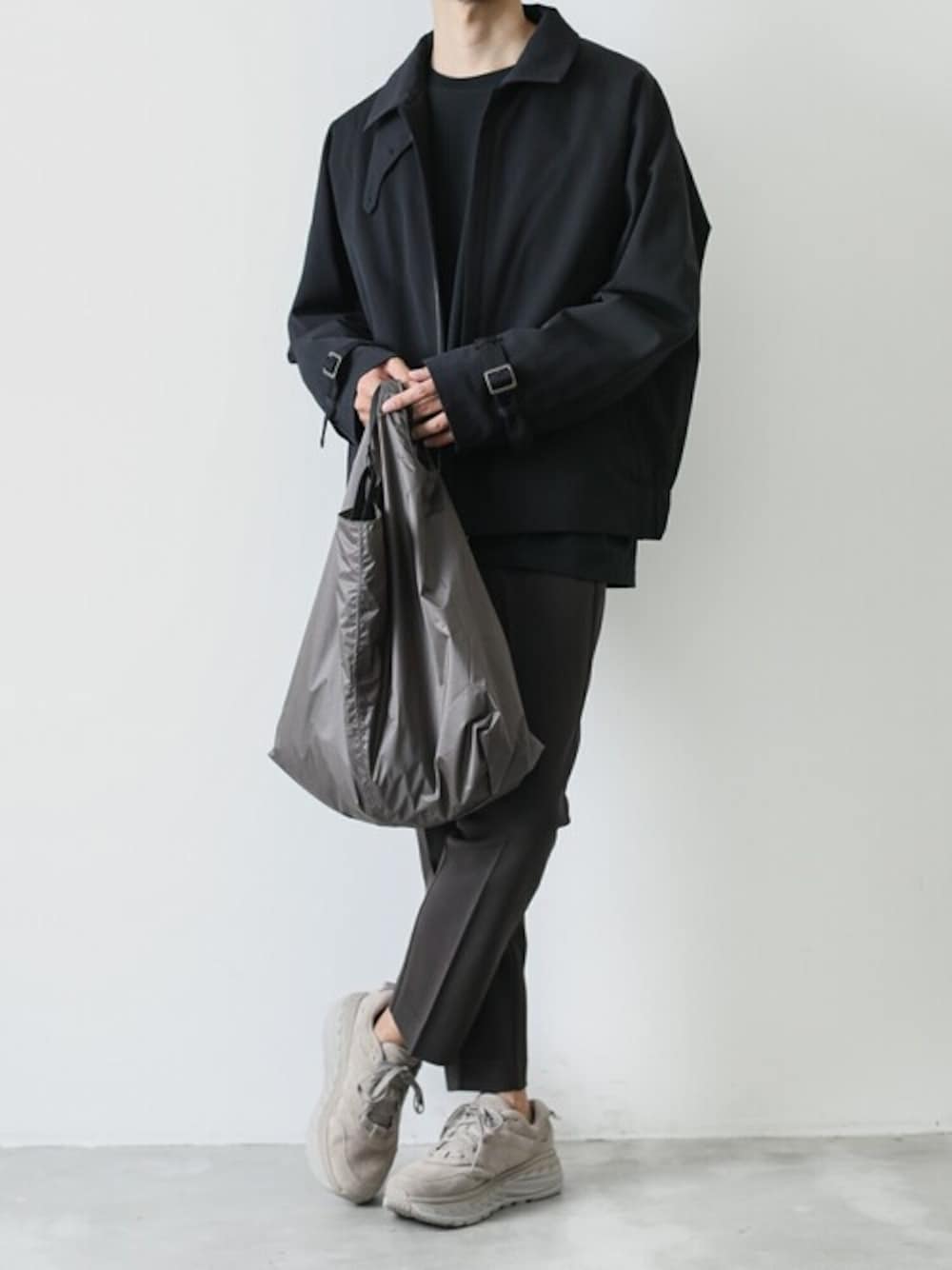 ブラック系のブルゾン、ブラック系のTシャツ/カットソー、ブラウン系のスラックスを着用したメンズの秋コーディネートの1枚目の写真