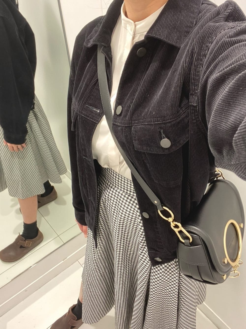 ブラック系のジャケット/アウター、ホワイト系のシャツ/ブラウス、ブラック系のショルダーバッグを着用したレディースの冬コーディネートの1枚目の写真