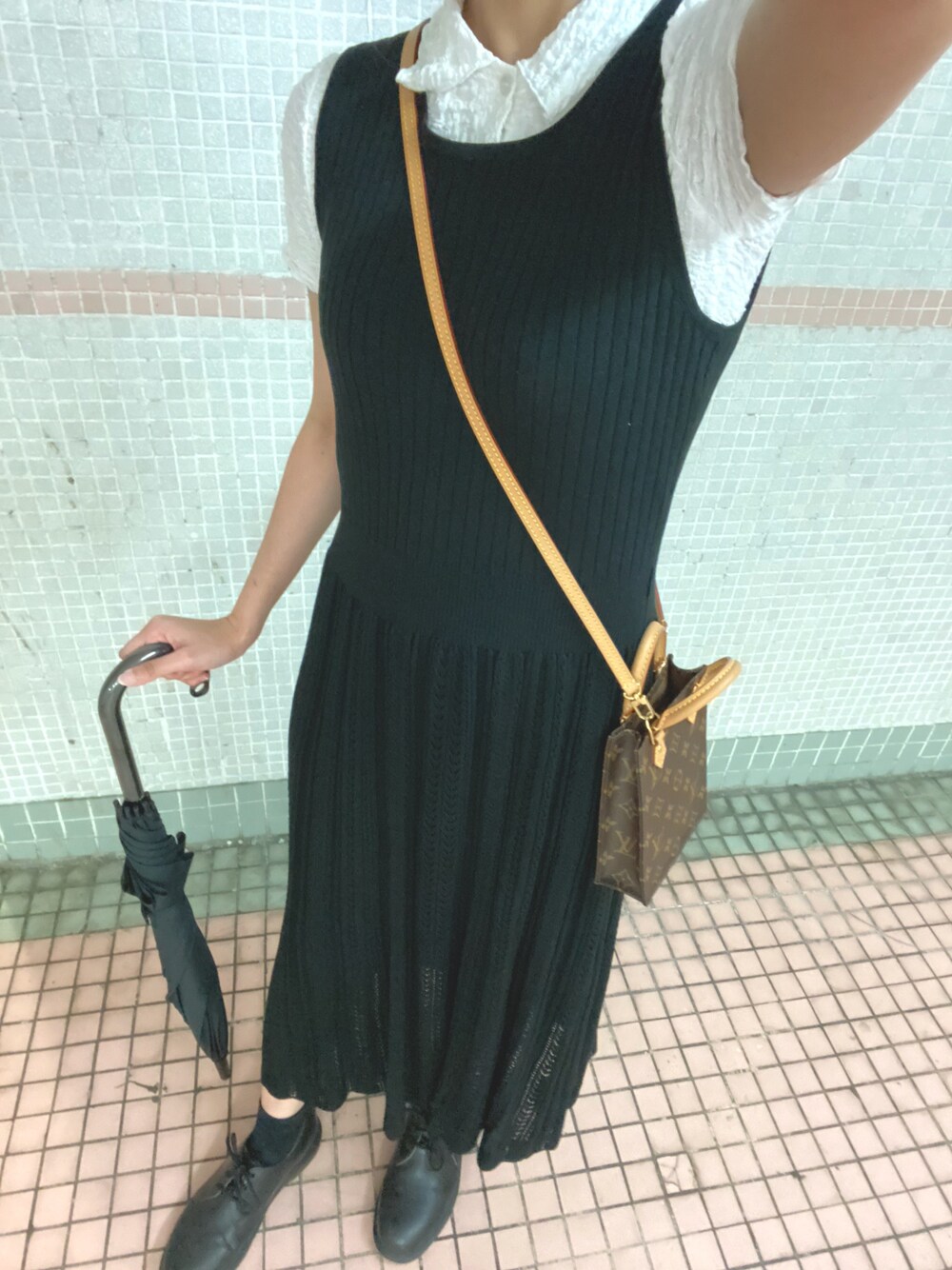 ホワイト系のトップス、ブラック系のスカート、ブラウン系のバッグを着用したレディースの春コーディネートの1枚目の写真