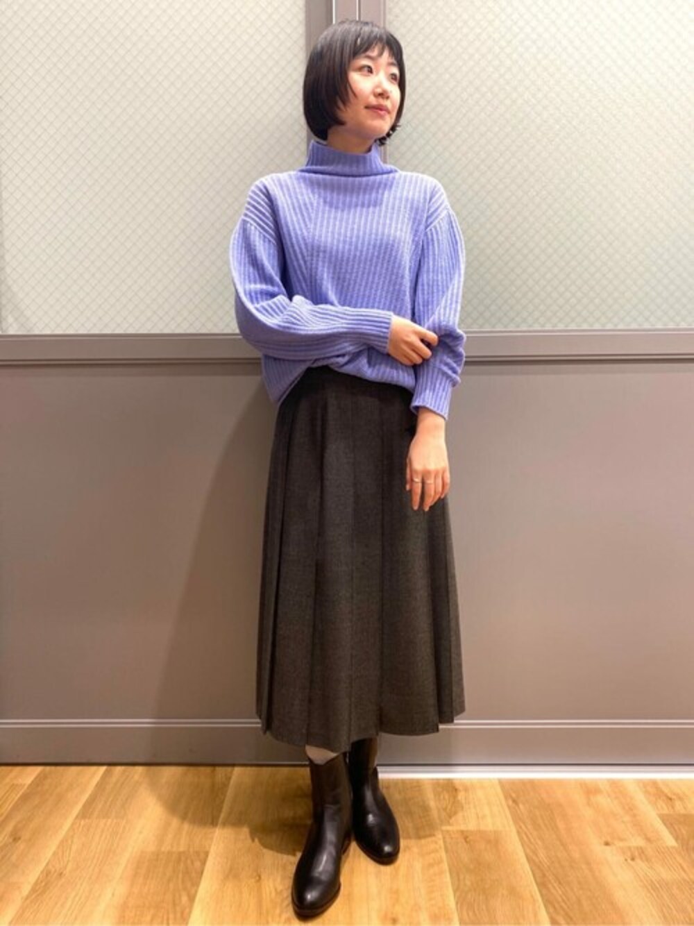 ブルー系のニット/セーター、グレー系のスカート、ブラック系のブーツを着用したレディースの冬コーディネートの1枚目の写真