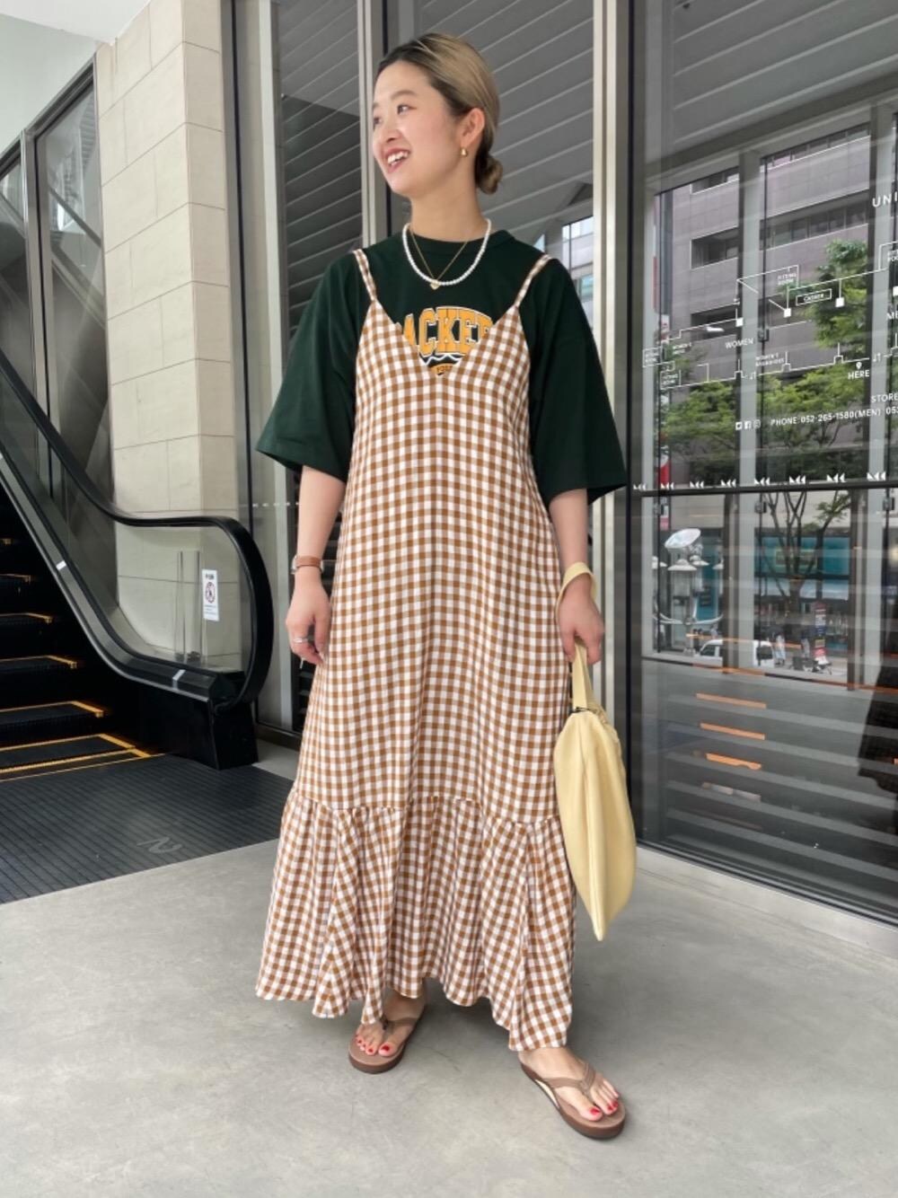 ベージュ系のワンピース、グリーン系のTシャツ/カットソー、ブラウン系のサンダルを着用したレディースの春コーディネートの1枚目の写真