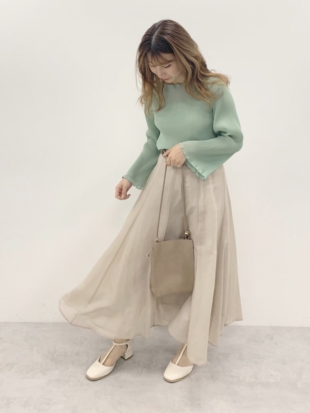 グリーン系のシャツ/ブラウス、ホワイト系のパンプス、ベージュ系のショルダーバッグを着用したレディースの春コーディネートの1枚目の写真