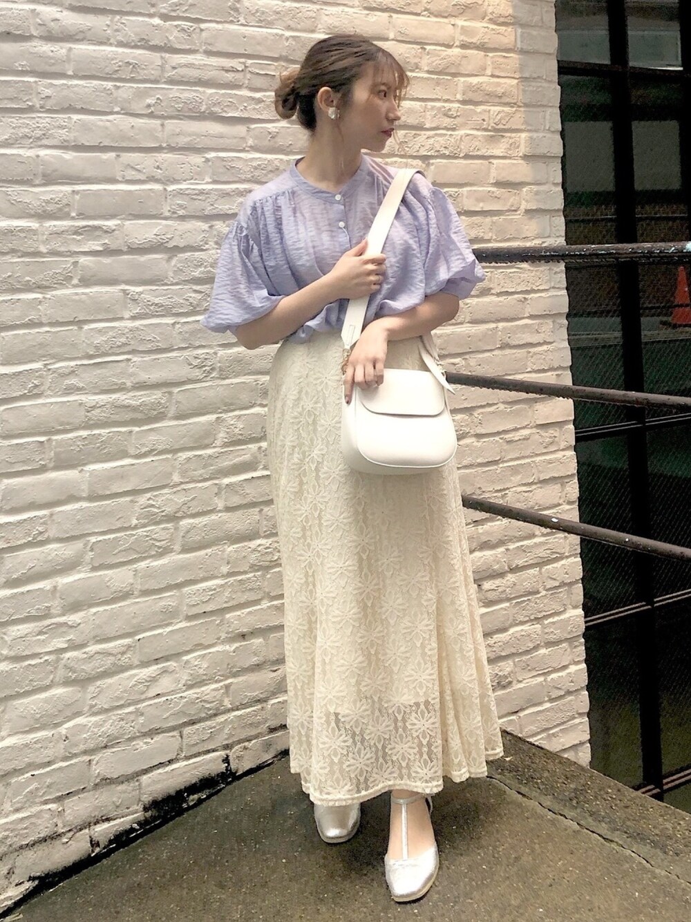 ホワイト系のスカート、シルバー系のパンプス、ホワイト系のショルダーバッグを着用したレディースの春コーディネートの1枚目の写真