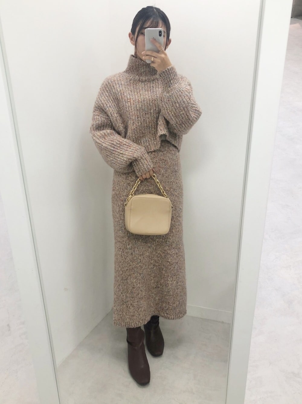 ピンク系のニット/セーター、ピンク系のスカート、ブラウン系のブーツを着用したレディースの秋コーディネートの1枚目の写真