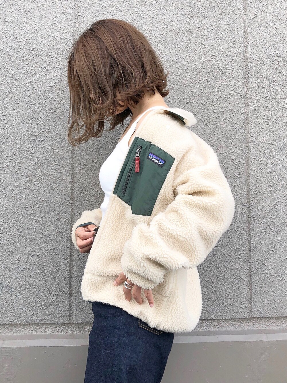 ベージュ系のブルゾン、ホワイト系のタンクトップ、ブルー系のデニムパンツを着用したレディースの秋コーディネートの1枚目の写真