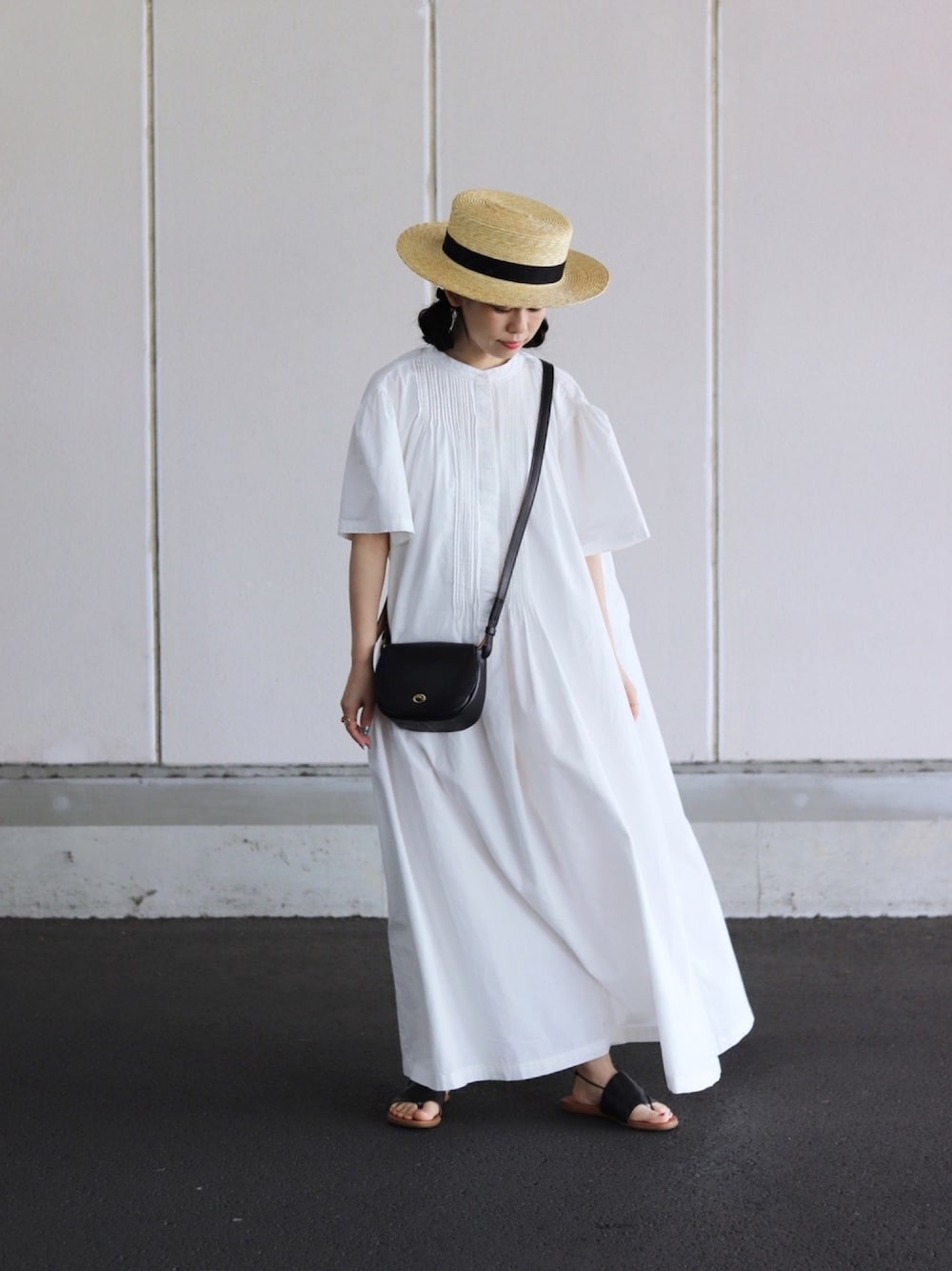ホワイト系のワンピース、ブラック系のバッグ、ブラック系のサンダルを着用したレディースの春コーディネートの1枚目の写真
