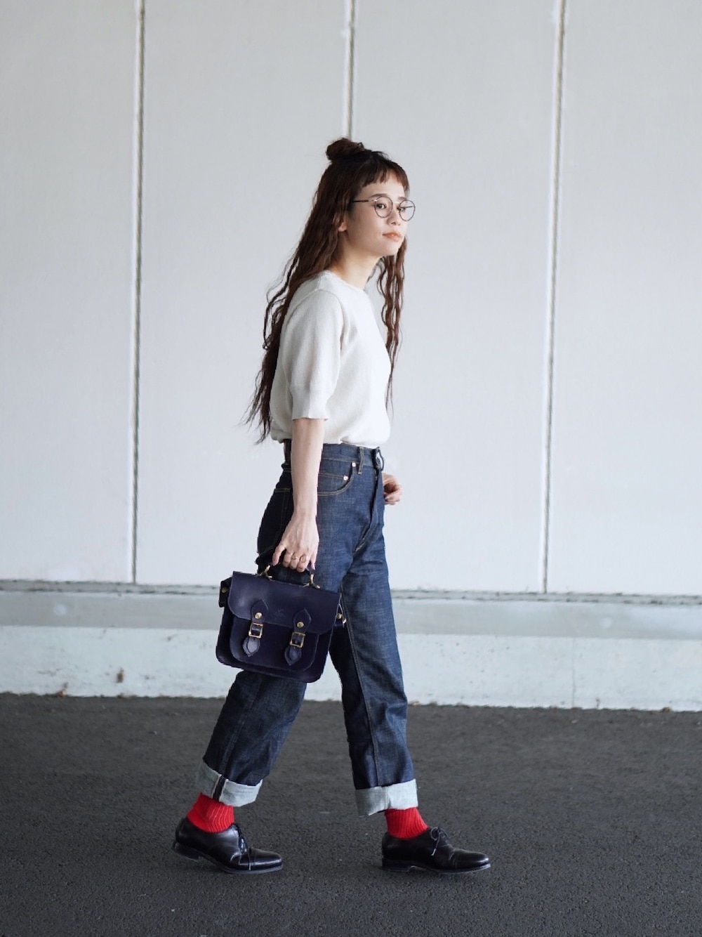 ベージュ系のトップス、ブルー系のデニムパンツ、ブルー系のショルダーバッグを着用したレディースの春コーディネートの1枚目の写真