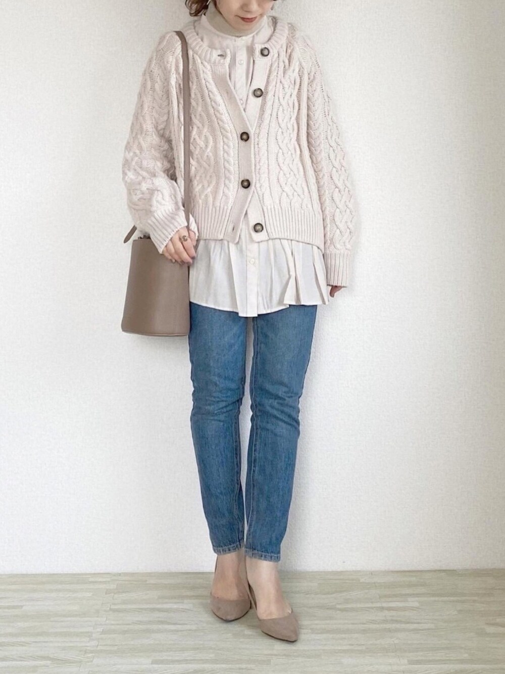 ベージュ系のカーディガン/ボレロ、ブルー系のデニムパンツ、ブラウン系のショルダーバッグを着用したレディースの冬コーディネートの1枚目の写真