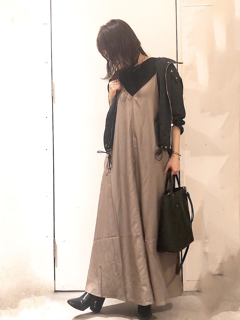 ベージュ系のワンピース、ブラック系のマウンテンパーカー、ブラック系のブーツを着用したレディースの秋コーディネートの1枚目の写真