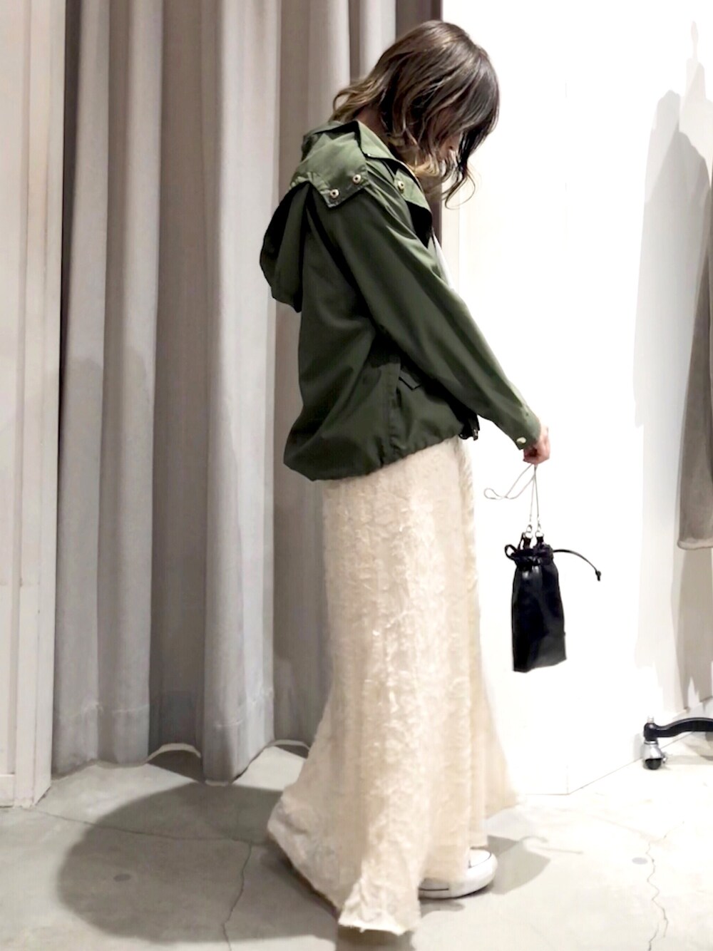 ベージュ系のスカート、グリーン系のマウンテンパーカー、ブラック系のショルダーバッグを着用したレディースの冬コーディネートの1枚目の写真