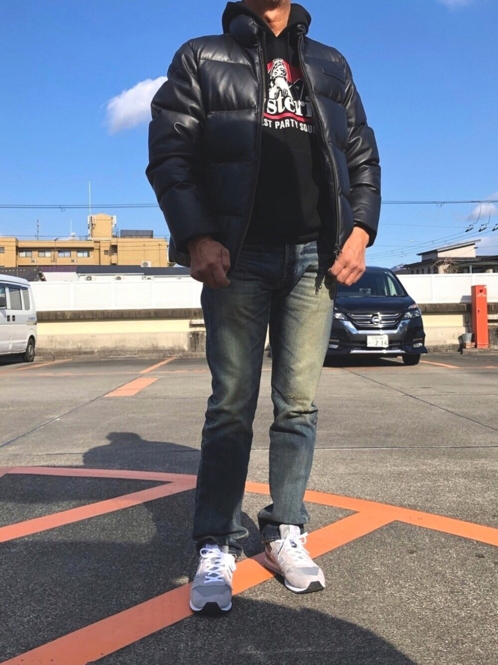 ブラック系のダウンジャケット/コート、ブラック系のパーカー、ブルー系のデニムパンツを着用したメンズの冬コーディネートの1枚目の写真
