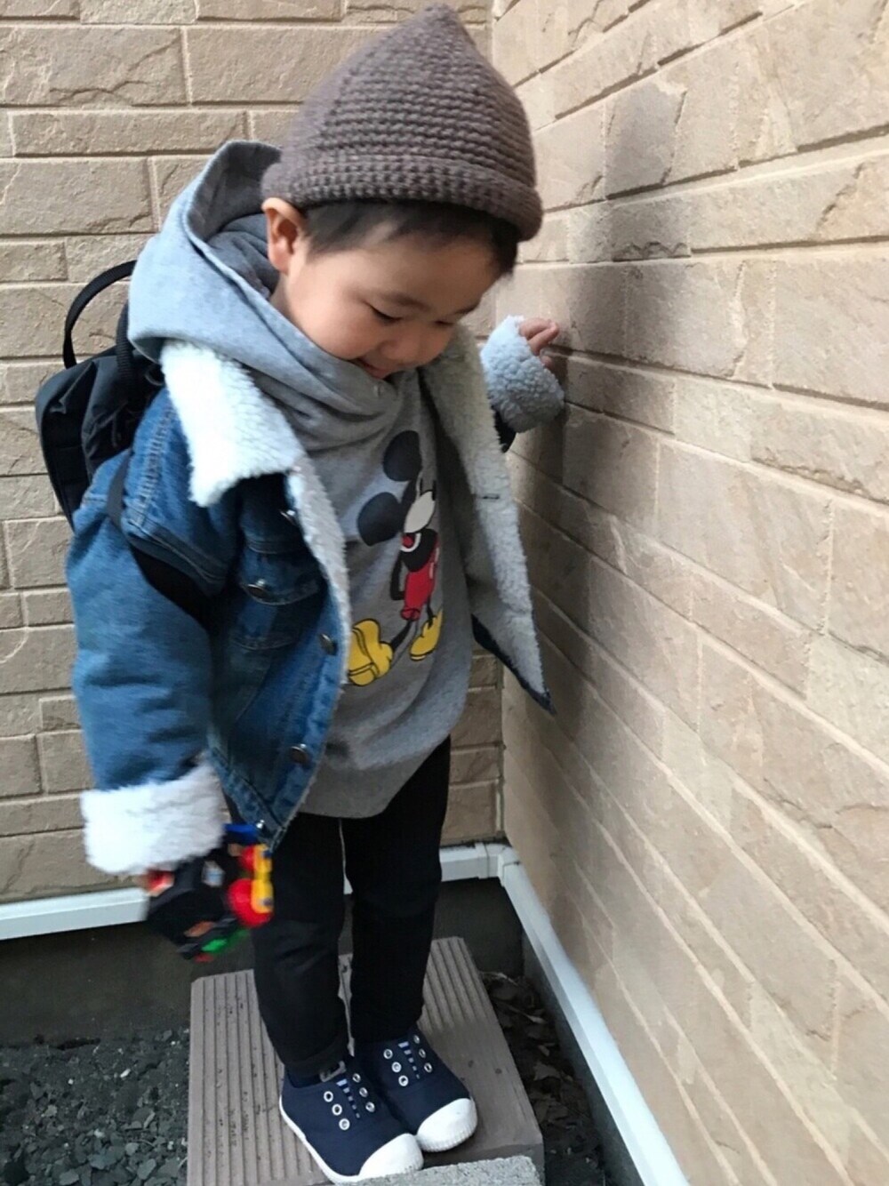 ブラック系のバックパック/リュック、グレー系のスウェット、ブルー系のデニムジャケットを着用したキッズの春コーディネートの1枚目の写真