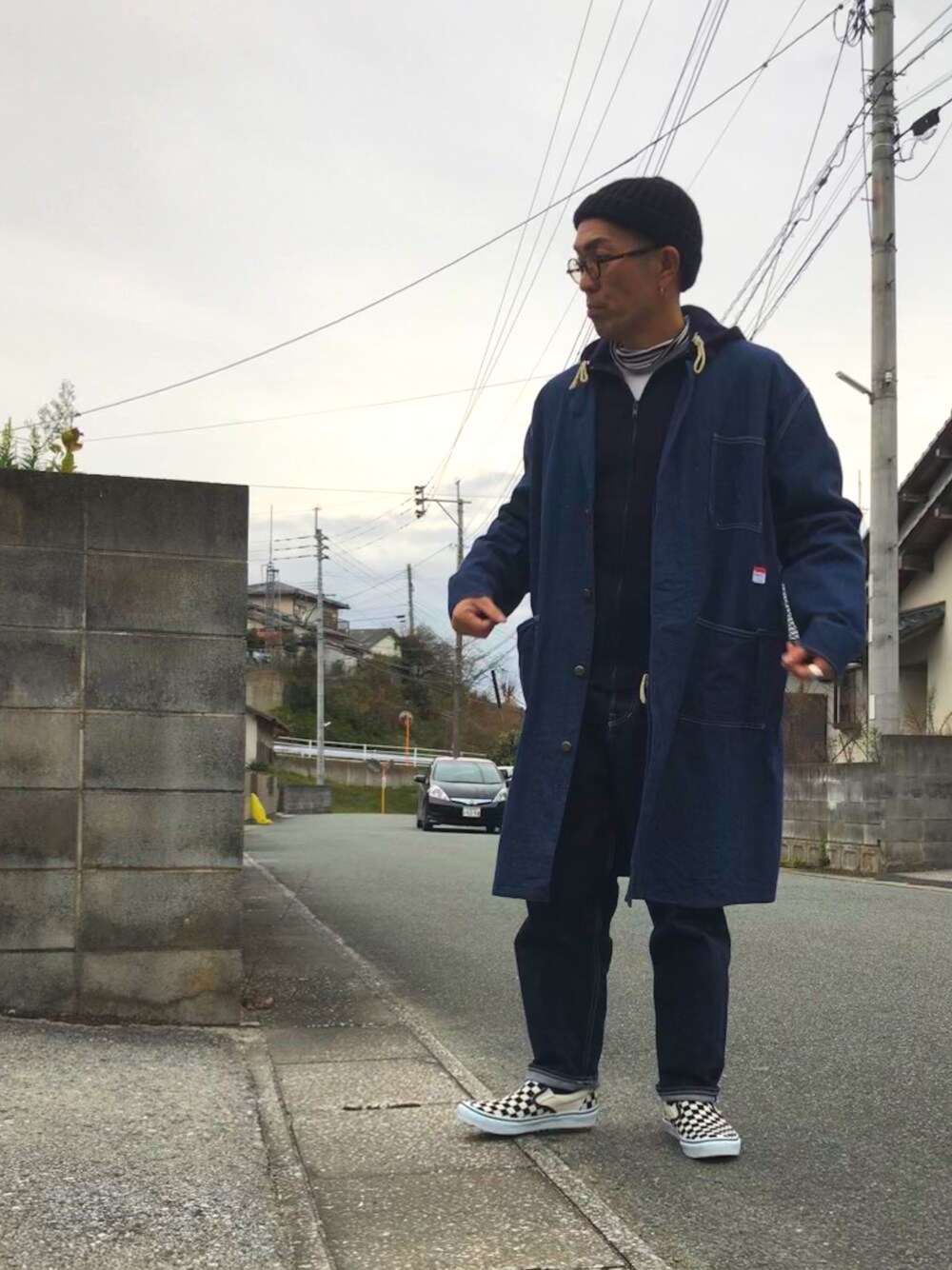 ブルー系のカバーオール、ブルー系のデニムパンツ、ブラック系のスリッポンを着用したメンズの冬コーディネートの1枚目の写真