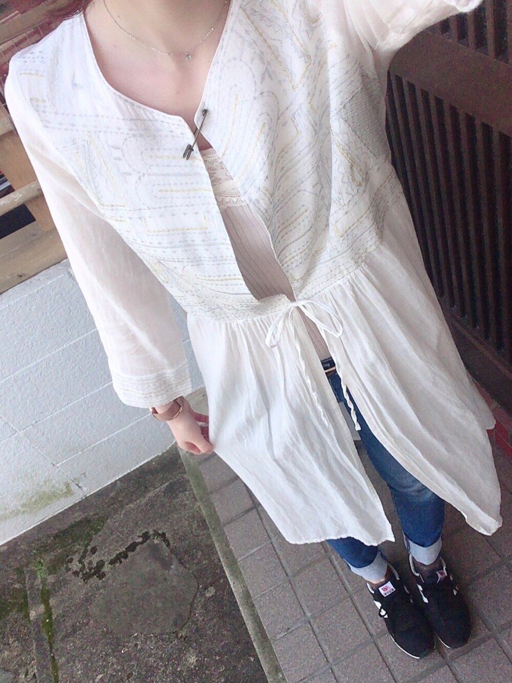 ホワイト系のワンピース/ドレス、ブルー系のデニムパンツ、ブラック系のスニーカーを着用したレディースの春コーディネートの1枚目の写真