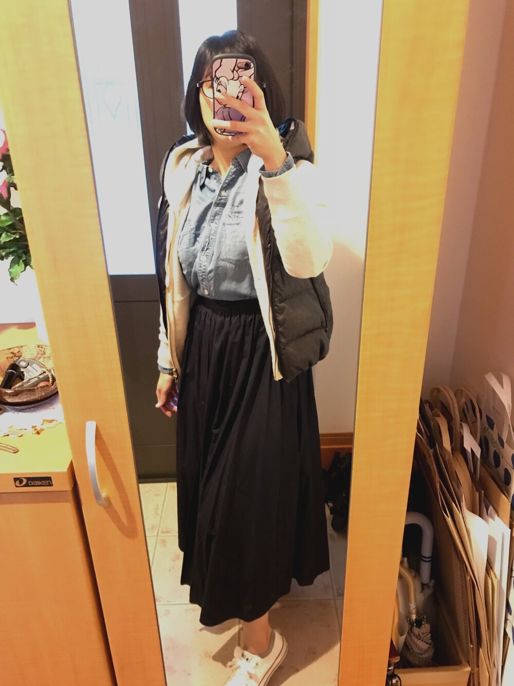 グレー系のダウンベスト、ベージュ系のパーカー、ブルー系のシャツ/ブラウスを着用したレディースの秋コーディネートの1枚目の写真