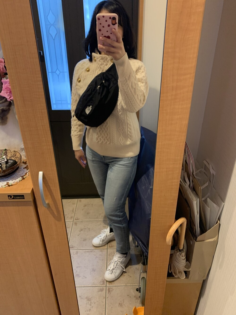 ベージュ系のニット/セーター、ブルー系のデニムパンツ、ホワイト系のスニーカーを着用したレディースの冬コーディネートの1枚目の写真