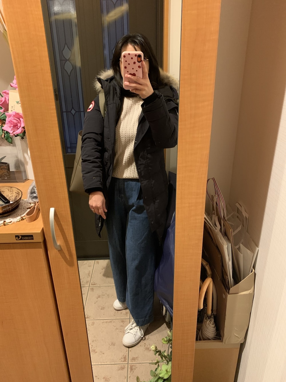 ブルー系のダウンジャケット/コート、ベージュ系のニット/セーター、ブルー系のデニムパンツを着用したレディースの冬コーディネートの1枚目の写真