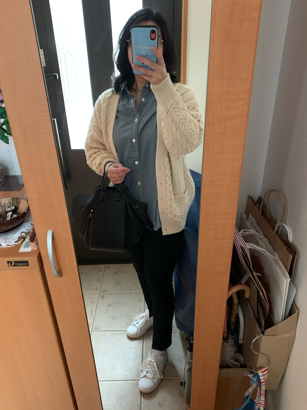 ブルー系のシャツ/ブラウス、ホワイト系のカーディガン/ボレロ、ブラック系のデニムパンツを着用したレディースの春コーディネートの1枚目の写真