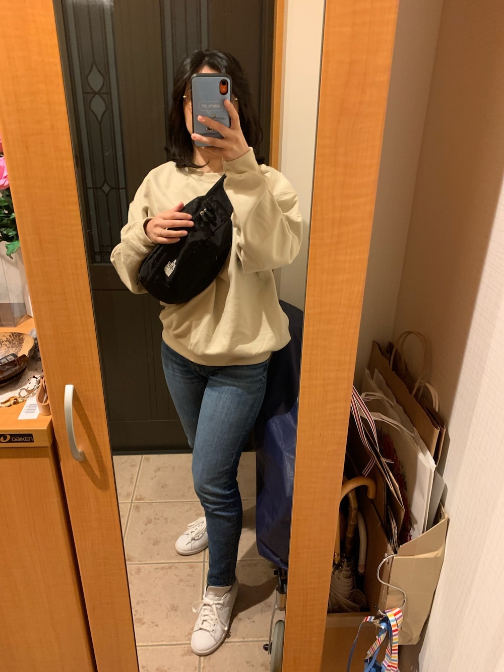 ベージュ系のスウェット、ブルー系のデニムパンツ、ホワイト系のスニーカーを着用したレディースの春コーディネートの1枚目の写真