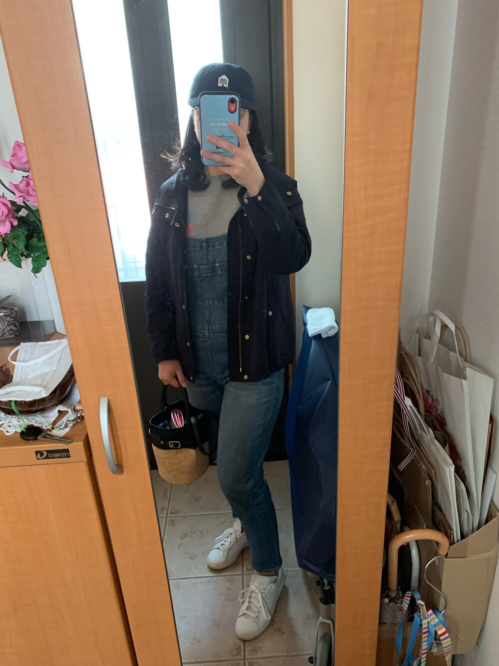 ブルー系のマウンテンパーカー、ブルー系のサロペット/オーバーオール、ホワイト系のスニーカーを着用したレディースの春コーディネートの1枚目の写真