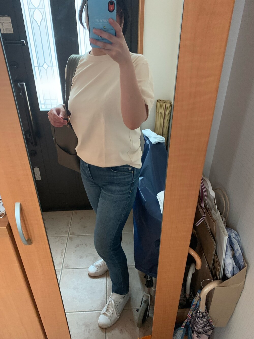 ブルー系のデニムパンツ、ベージュ系のTシャツ/カットソー、ホワイト系のスニーカーを着用したレディースの夏コーディネートの1枚目の写真