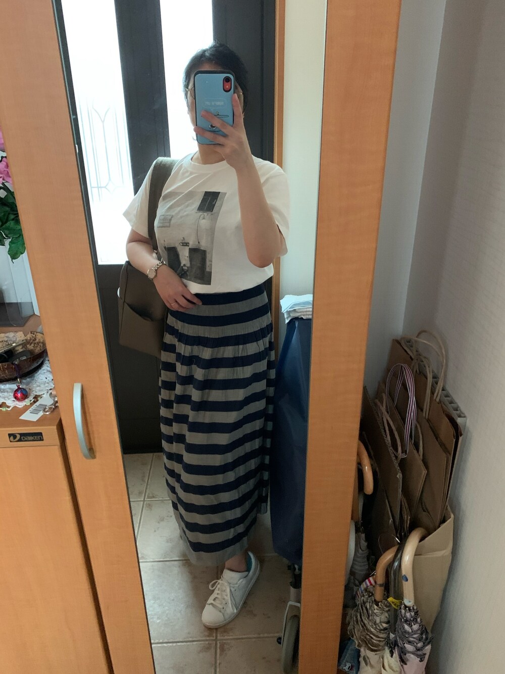 ブルー系のスカート、ホワイト系のTシャツ/カットソー、ベージュ系のショルダーバッグを着用したレディースの夏コーディネートの1枚目の写真