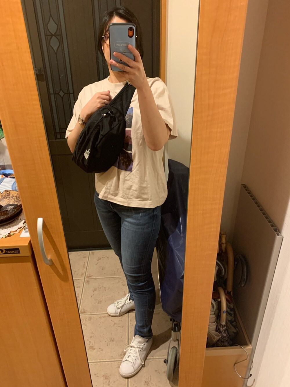 ベージュ系のTシャツ/カットソー、ブルー系のデニムパンツ、ホワイト系のスニーカーを着用したレディースの秋コーディネートの1枚目の写真