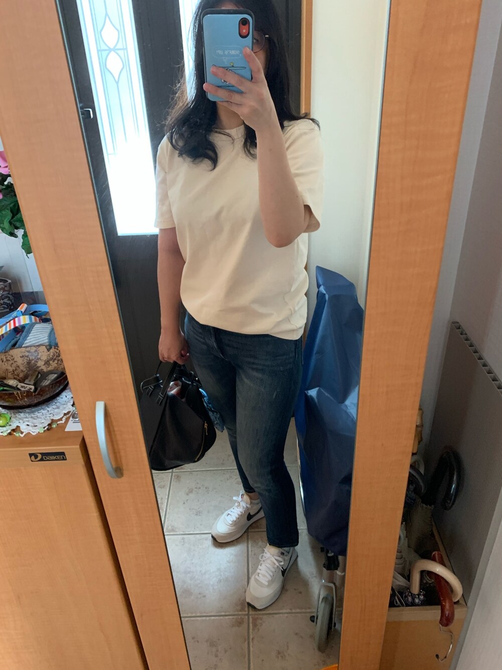 ベージュ系のTシャツ/カットソー、ブルー系のデニムパンツ、ホワイト系のスニーカーを着用したレディースの秋コーディネートの1枚目の写真