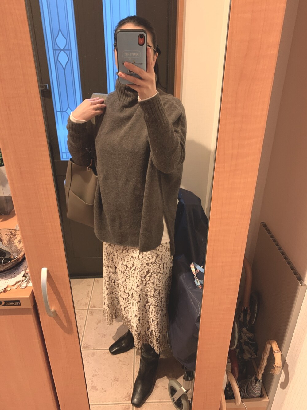 グレー系のニット/セーター、ホワイト系のTシャツ/カットソー、ベージュ系のスカートを着用したレディースの冬コーディネートの1枚目の写真