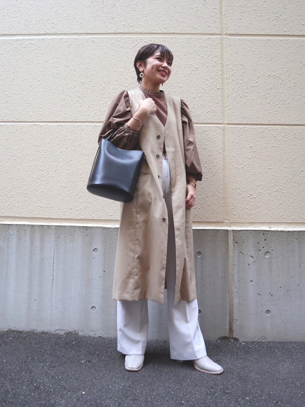 ベージュ系のノーカラーコート、ブラウン系のシャツ/ブラウス、ブラック系のショルダーバッグを着用したレディースの秋コーディネートの1枚目の写真