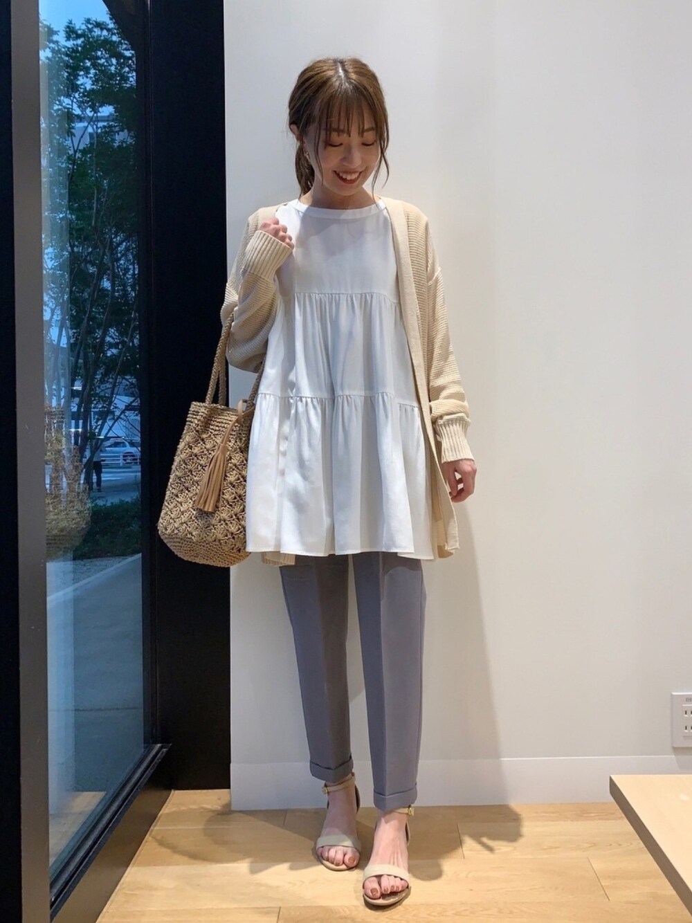 ホワイト系のチュニック、ホワイト系のカーディガン/ボレロ、グレー系のその他パンツを着用したレディースの春コーディネートの1枚目の写真