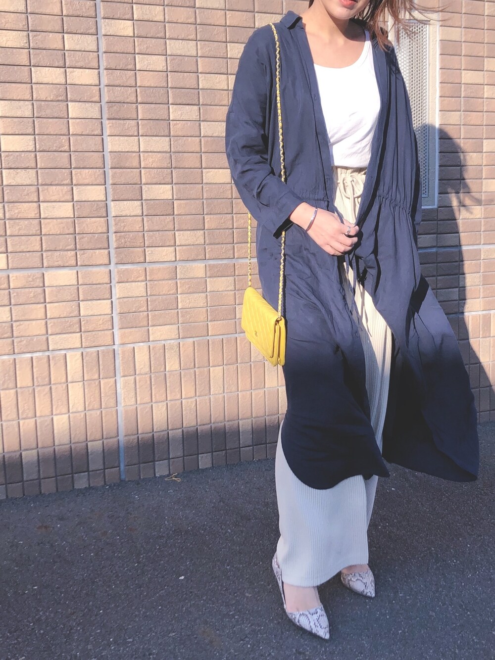 イエロー系のショルダーバッグ、ブルー系のシャツワンピース、ベージュ系のその他パンツを着用したレディースの春コーディネートの1枚目の写真